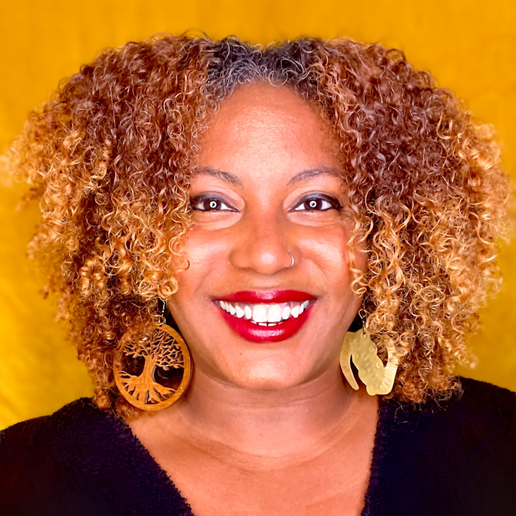 Headshot of Faylita Hicks, smiling wearing a black top and red lipstick.