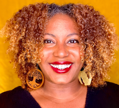 Headshot of Faylita Hicks, smiling wearing a black top and red lipstick.