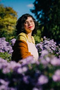 flower field with Natasha centered in front of trees and open sky.